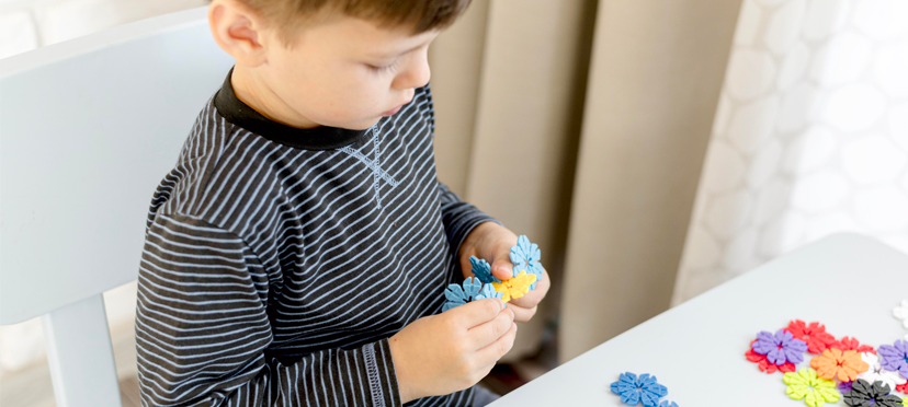 Enfant assemblant des pièces de puzzle simples sous la supervision d'une éducatrice.