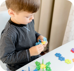 Enfant assemblant des pièces de puzzle simples sous la supervision d'une éducatrice.