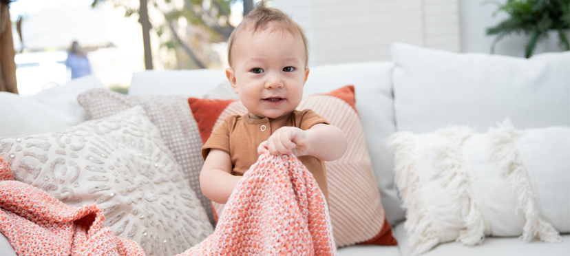 Bébé jouant à cache-cache avec un jouet caché sous une couverture.