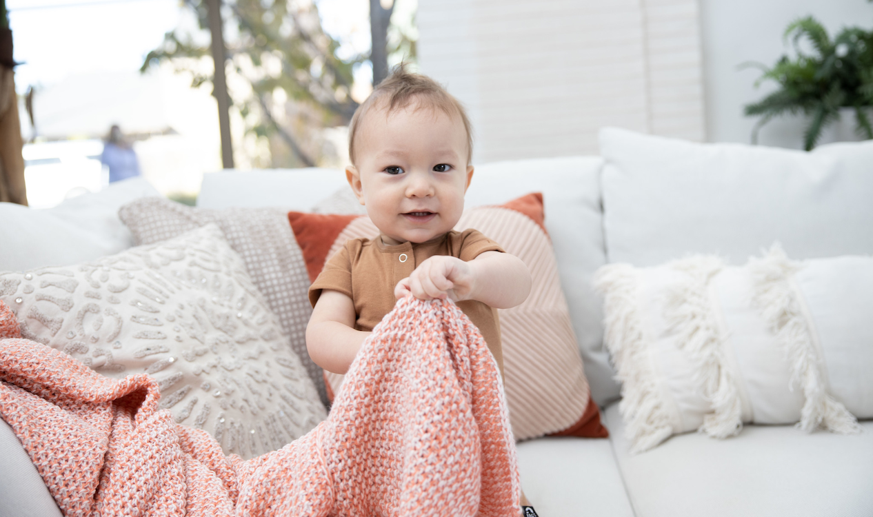 Bébé jouant à cache-cache avec un jouet caché sous une couverture.