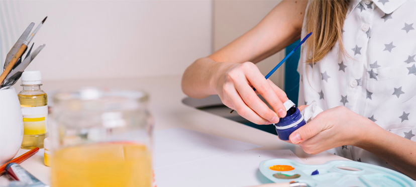 Enfant tamponnant des paniers dans de la peinture pour créer des formes sur papier.