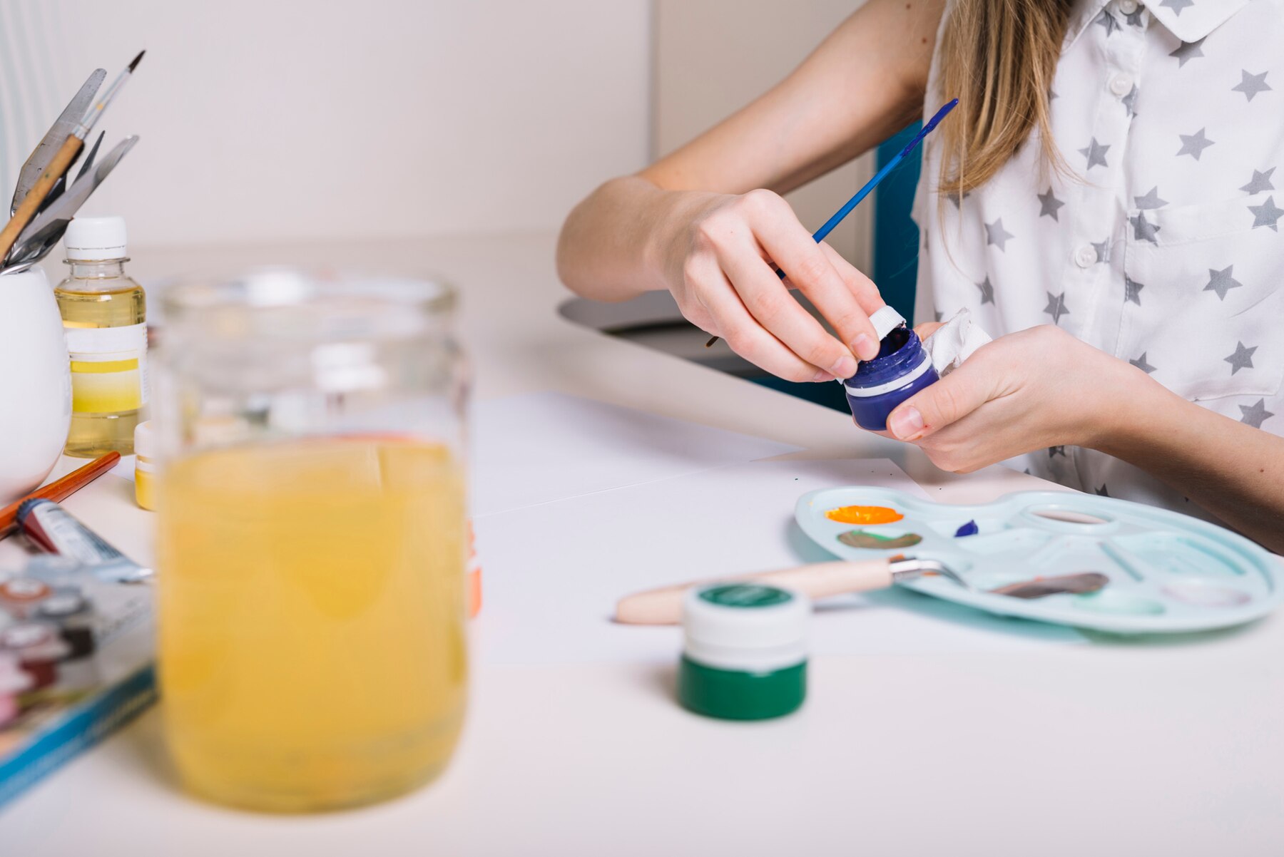 Enfant tamponnant des paniers dans de la peinture pour créer des formes sur papier.